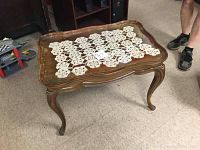 Wooden end table with crochet runner seen from an angle showing legs and top surface