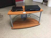 TV stand with two wooden shelves and one glass shelf, with a Toshiba DVD player and another electronic device on top