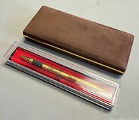 Gold Dunhill pen in clear case beside brown case