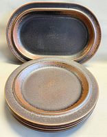 Stack of seven plates with oval platter in background