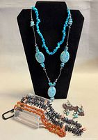 Two turquoise necklaces displayed on bust; chip strand and oval bead strand