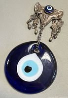 Overall view of blue glass evil eye disc hanging from metal mount