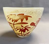 Front view of conical art glass bowl showing red floral motif on pale yellow background
