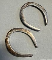 Both silver horseshoe-shaped napkin rings front view