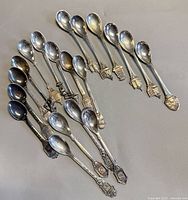19 assorted silver plated souvenir spoons displayed in arcs
