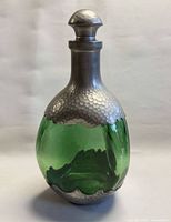 Front view of green glass decanter with hammered pewter overlay and stopper