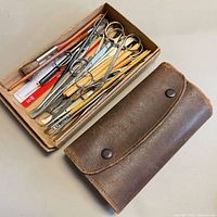closed brown leather roll next to box of loose instruments