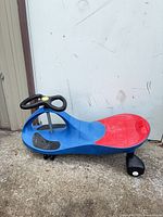 Top view of blue ride-on wiggle car with red seat and steering wheel