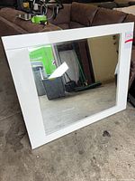 Front view of white framed mirror leaning against wall