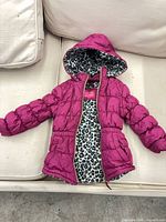 Front view of magenta hooded puffer jacket showing leopard lining and overall style