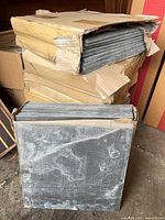 Stack of opened but sealed tile boxes showing gray tiles