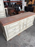 Front view showing nine drawers, natural wood top, cream body, metal pulls