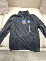 Front view of charcoal fleece jacket showing quarter zipper and tags attached