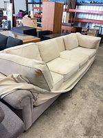 Full view of sectional sofa with off-white slipcover and loose cushions