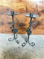 Front view of both silver/grey wrought iron candle holders showing vine and leaf details