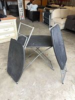 Three folding tray tables standing, two folded, one open