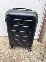 Front view of Solgaard dark gray/black carry-on spinner suitcase showing hard shell and horizontal ribs.