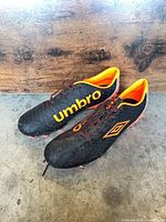 Pair of Umbro black soccer cleats side view showing exterior logos and studs
