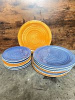 Stacks of orange and blue dinner and salad plates showing quantity and colors