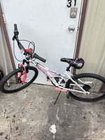 Full view of white 26" bicycle leaning against door