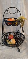 Front view of two tier wrought iron stand with fruit for scale