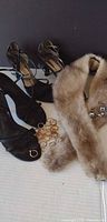 Two pairs black strappy heels, fur collar, rings and earrings displayed