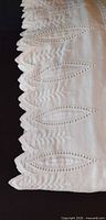 Close-up of scalloped cutwork leaf edge on white fabric