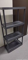 Full view of one dark grey plastic shelving unit showing four shelves