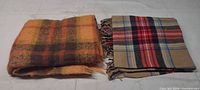 Both folded plaid blankets side by side