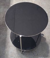 Top view showing round black glass top shelf within metal frame