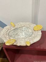 Top view of ceramic dish showing speckled interior, irregular rim, yellow accents