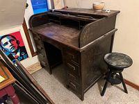 Front angled view of wood roll-top style desk showing drawers, cubbies and worn surface