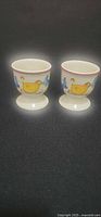 Front view of both egg cups showing yellow bird and blue butterfly pattern