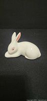 Side view of white ceramic rabbit figurine, showing pink ear accent and eye