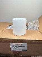 single white tumbler jar displayed on sealed CandleScience case