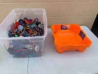 clear tote filled with assorted Beyblade tops and orange arena