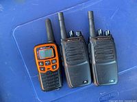 Front view of three Midland walkie talkies on blue surface