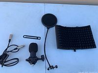 Top view of microphone with cable, bracket, pop filter, and folded acoustic foam shield