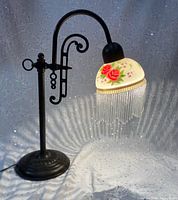 Lamp lit, showing painted shade, bead fringe and stand