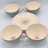 Top view showing 4 cups and saucers, starburst motif visible