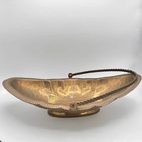 Side view of hammered brass basket showing handle and rim detail