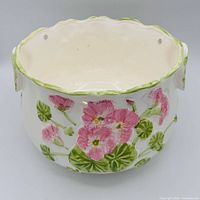 Front view of ceramic planter showing floral design and hanging holes