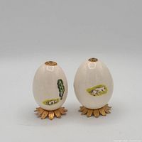 Front view showing both painted eggs on stands, grazing animal motifs visible