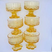 Stacked view of all six amber dessert dishes showing pedestal floral bases and bubble band detail