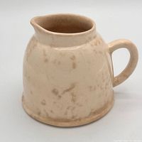 Side view of ivory glazed Arthur Wood earthenware creamer