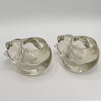 Two clear glass sleeping cat candle holders side by side