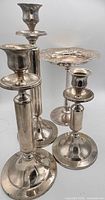 Group view of three candlesticks and compote standing upright