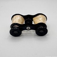 Front view of opera glasses showing black eyepieces and cream barrels