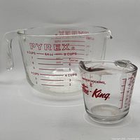 Front view of both measuring cups showing brand logos and graduations