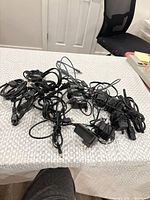 Group of tangled black laptop power adapters on table